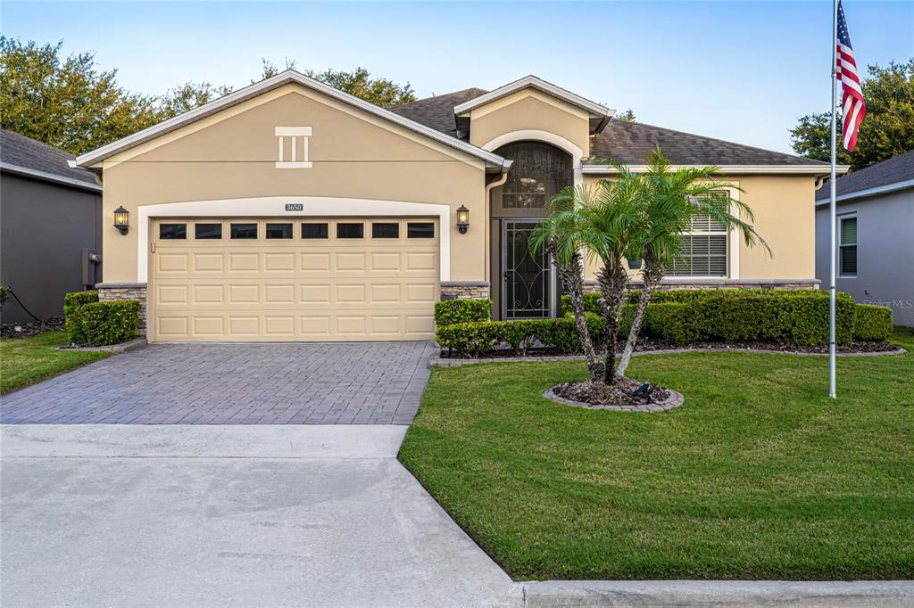 A single-story house with a tan stucco exterior, a two-car garage, and a front lawn — 3650 LIMESTONE STREET, CLERMONT, FL