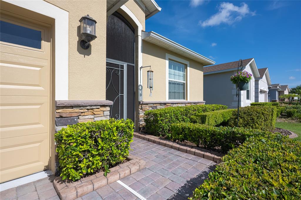 A paved walkway leads to the front entrance of a house with tan stucco siding — 3650 LIMESTONE STREET, CLERMONT, FL
