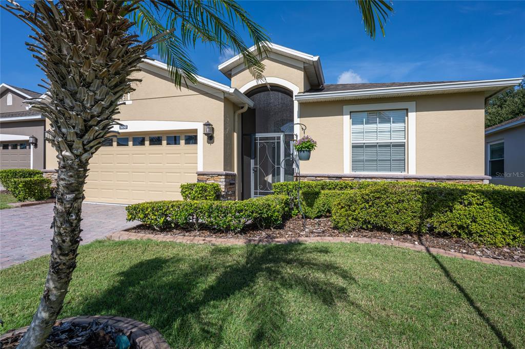 A single-story house with a tan stucco exterior, a two-car garage, and a front lawn — 3650 LIMESTONE STREET, CLERMONT, FL