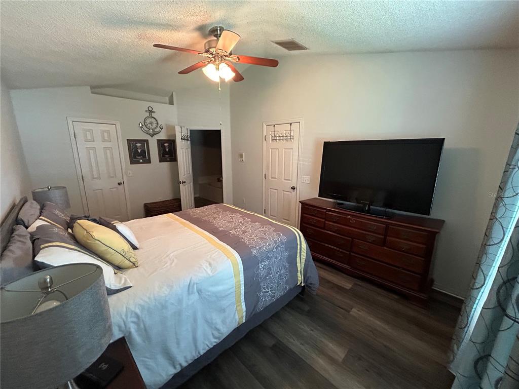 A bedroom features a bed, a dresser with a television, and a ceiling fan — 3243 BRETTON WOODS TERRACE, DELTONA, FL