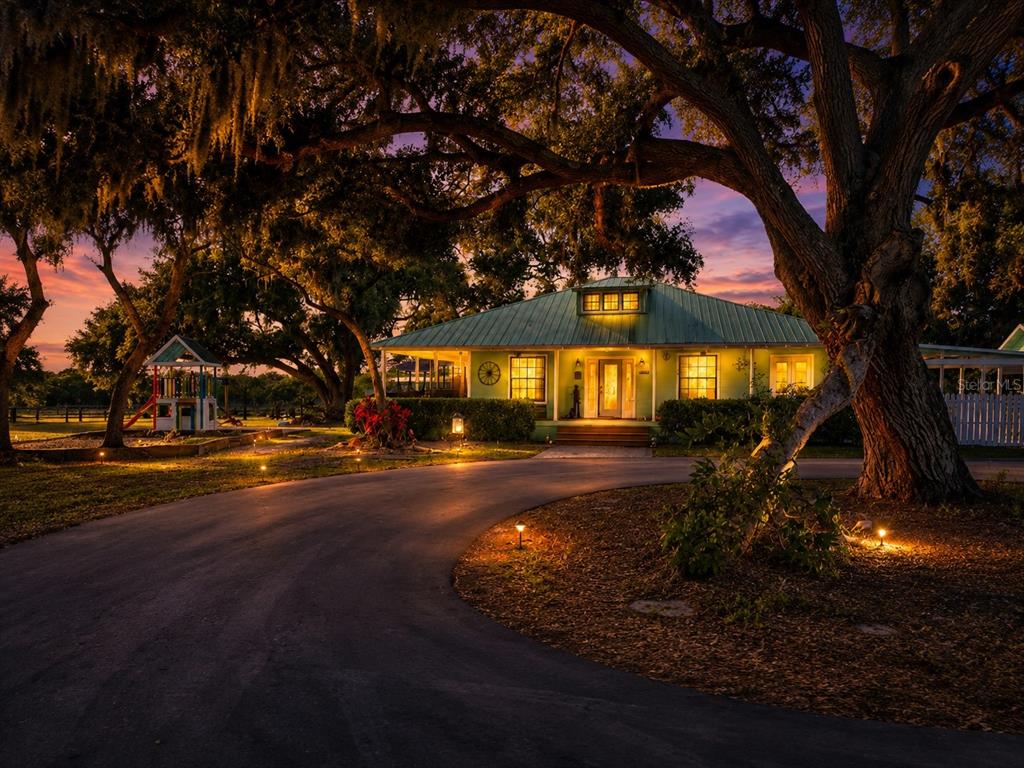 A paved driveway leads toward a house shaded by large oak trees on a lawn — 5925 SPENCER PARRISH ROAD, PARRISH, FL