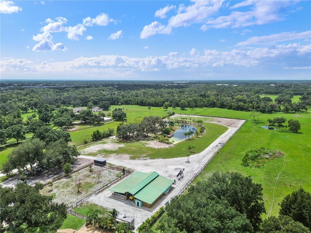 An aerial view shows a rural property with a pond, a barn, and gravel driveways — 5925 SPENCER PARRISH ROAD, PARRISH, FL