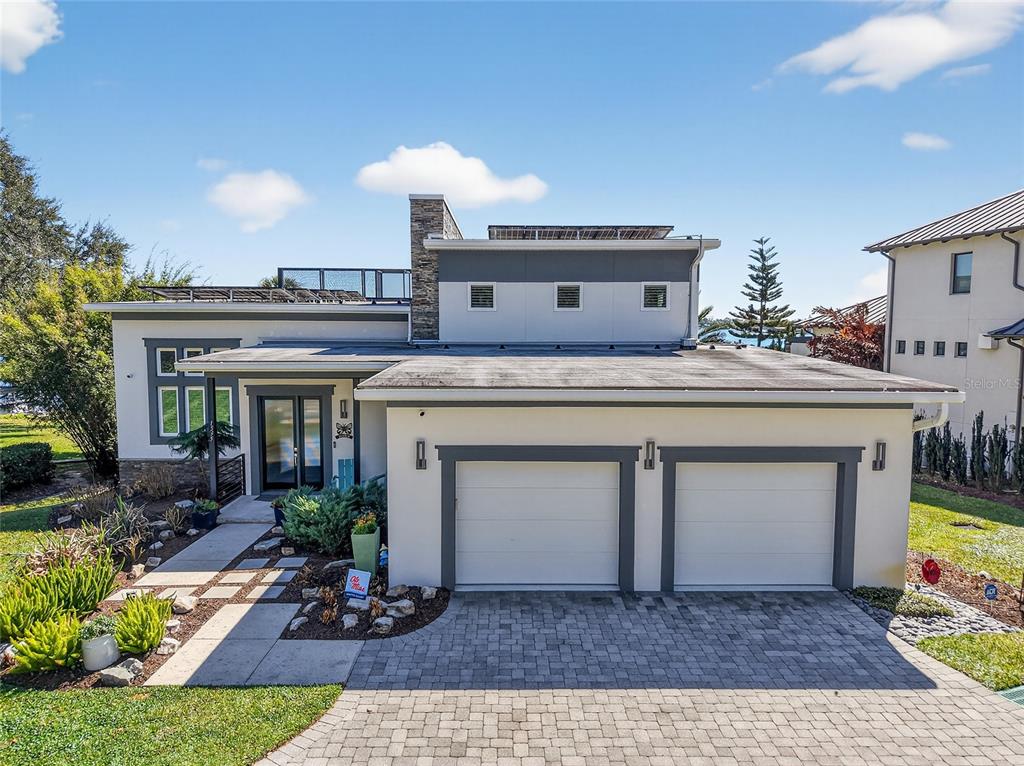 A modern two-story house with a flat roof, stone chimney, and two-car garage — 1535 SUNSET CIRCLE, MOUNT DORA, FL