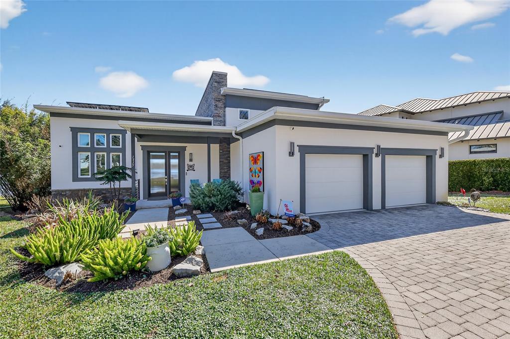 A modern single-story house features a stone chimney, two garage doors, and a paved driveway — 1535 SUNSET CIRCLE, MOUNT DORA, FL
