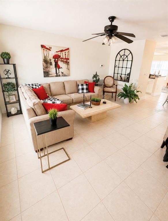 A living room features a beige sectional sofa, a coffee table, and tile flooring — 9021 41ST WAY N UNIT 0, PINELLAS PARK, FL