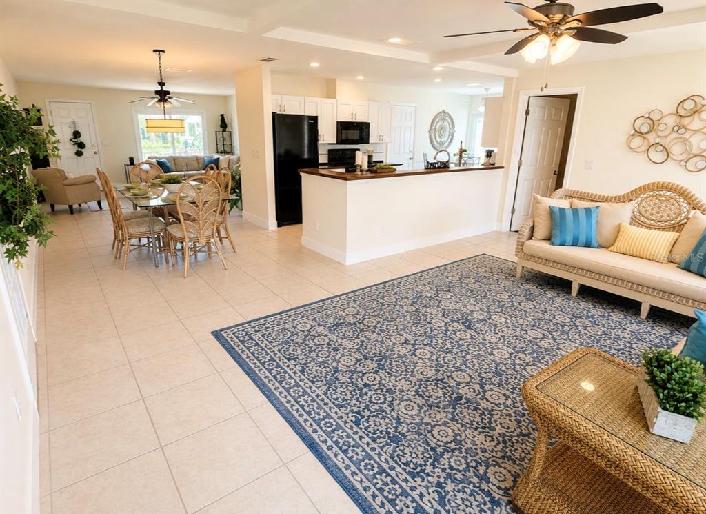 A living room features tiled floors, wicker furniture, a large area rug, and ceiling lighting — 9021 41ST WAY N UNIT 0, PINELLAS PARK, FL