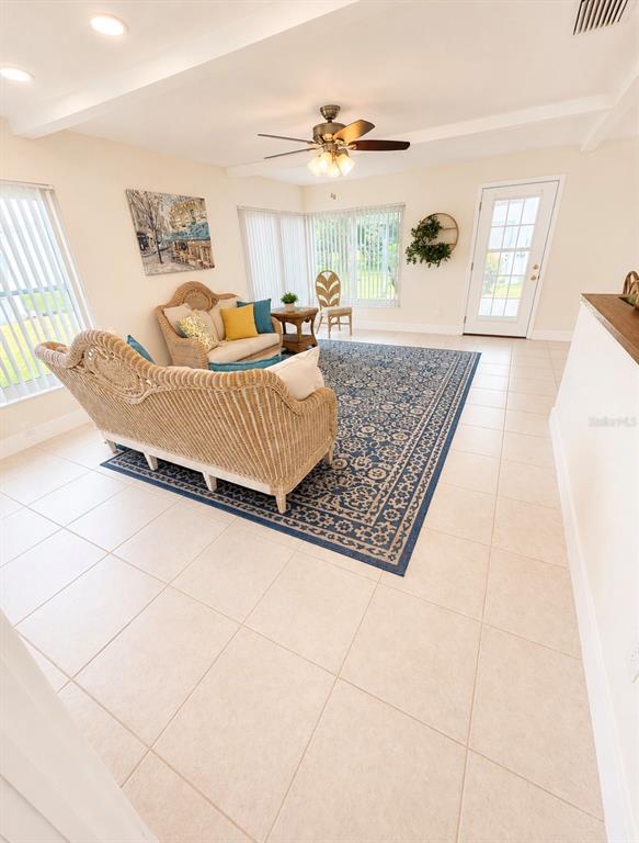 An open-concept living and dining area features tile flooring, a kitchen island, and wicker furniture — 9021 41ST WAY N UNIT 0, PINELLAS PARK, FL