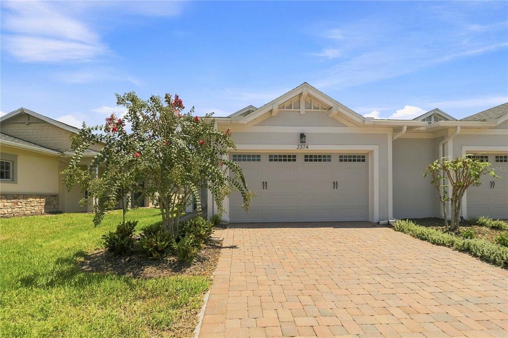 A single-story house exterior features a paved driveway, a two-car garage, and a small tree — 2374 DATURA LOOP, ST CLOUD, FL