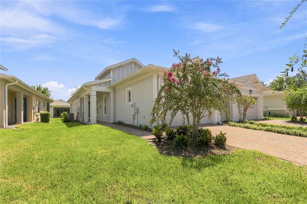 A light-colored single-story house with a brick driveway and a small flowering tree in front — 2374 DATURA LOOP, ST CLOUD, FL