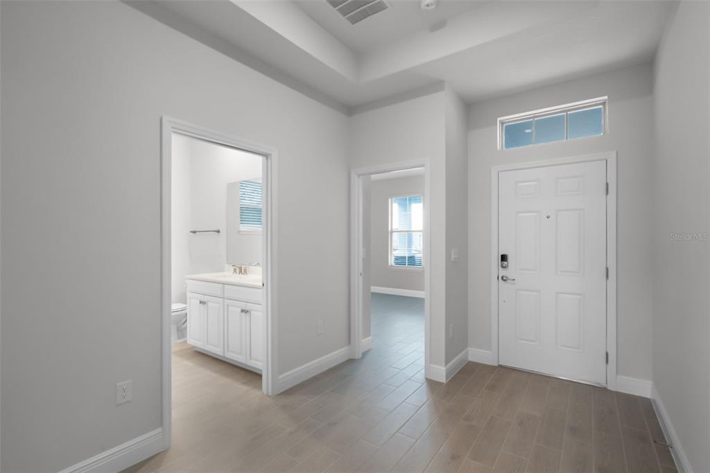 An entryway with light wood-look tile flooring, a white front door, and two interior doorways — 11923 SHINE VIEW LANE, WINTER GARDEN, FL