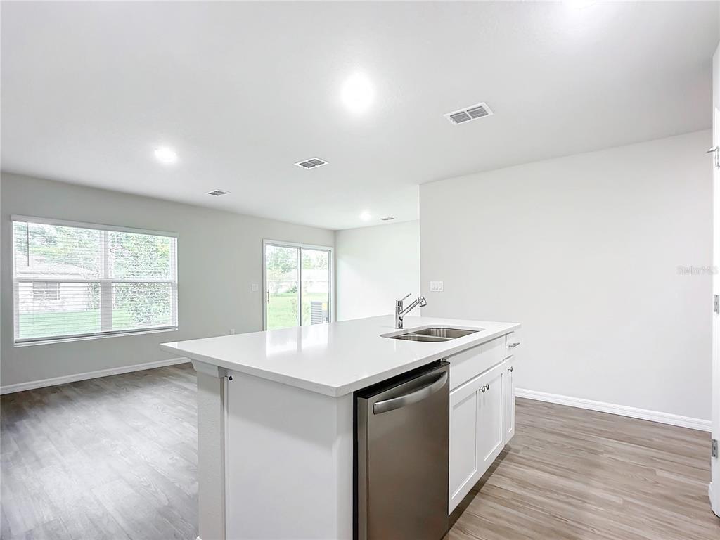 A kitchen island with a stainless steel dishwasher and sink sits in an open room — 54 UNDERWOOD TRAIL, PALM COAST, FL