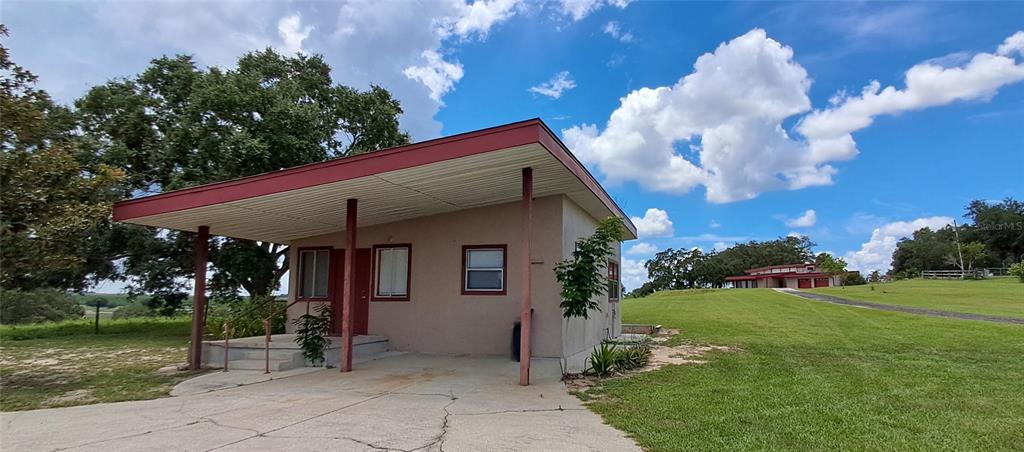 A red pergola extends from a beige house with two red garage doors — 2741 EDWARDS ROAD, HAINES CITY, FL