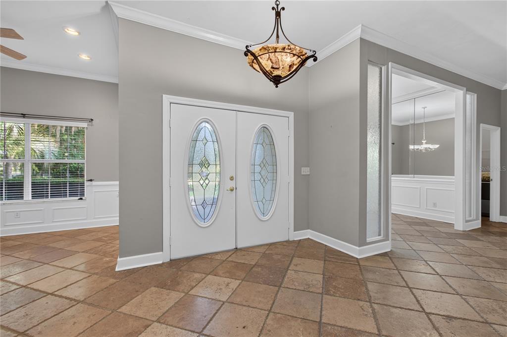 A spacious living room features a large leather sectional, tile flooring, and glass patio doors — 12208 SW 9TH AVENUE, NEWBERRY, FL