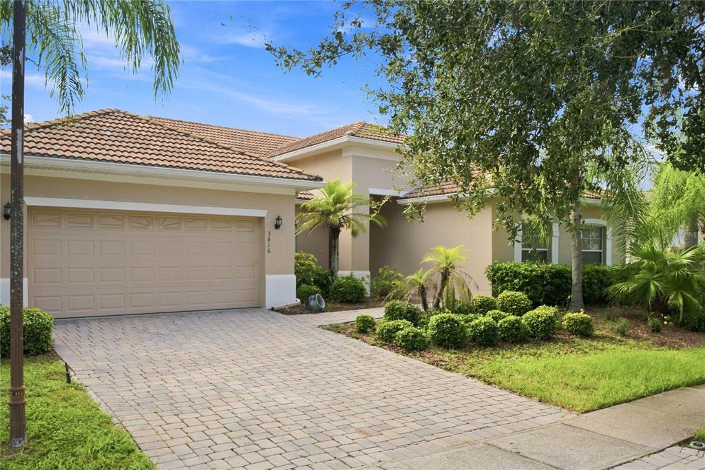 A beige single-story house with a tiled roof, a paved driveway, and landscaped front yard — 3616 VALLEYVIEW DRIVE, KISSIMMEE, FL