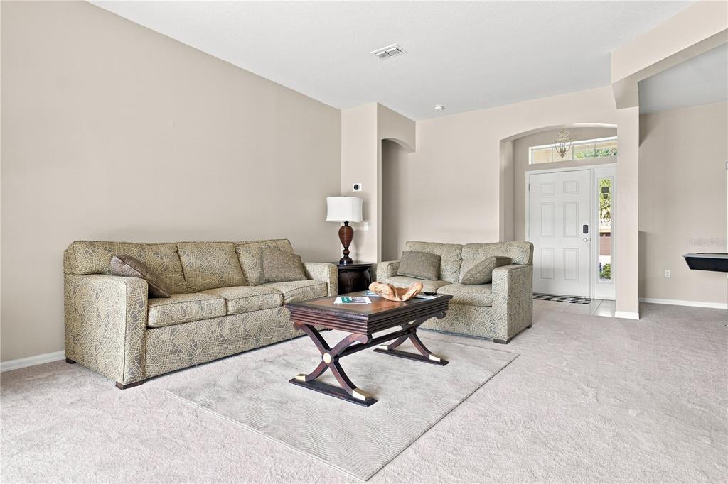 A living room features a patterned sofa and loveseat on a rug with a coffee table — 3616 VALLEYVIEW DRIVE, KISSIMMEE, FL