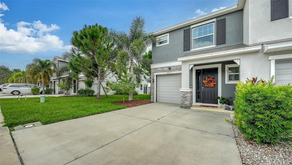 A two-story townhouse with a gray exterior, a single-car garage, and a small front yard — 2627 MIDNIGHT PEARL DRIVE, SARASOTA, FL