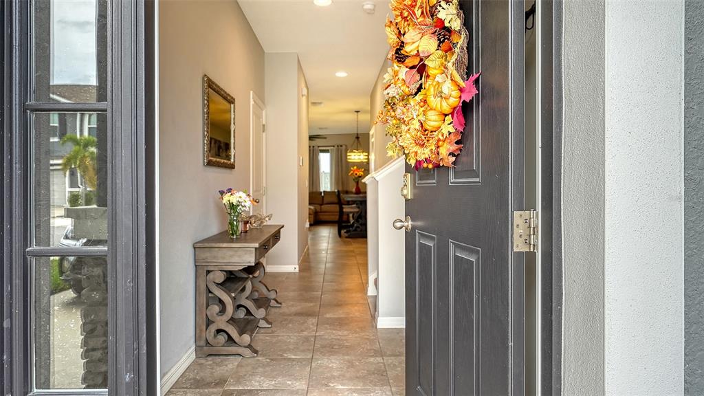 A view through an open front door into a tiled entryway with a console table — 2627 MIDNIGHT PEARL DRIVE, SARASOTA, FL