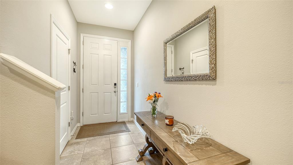 A foyer features a white front door, tiled floor, wooden console table, and wall mirror — 2627 MIDNIGHT PEARL DRIVE, SARASOTA, FL