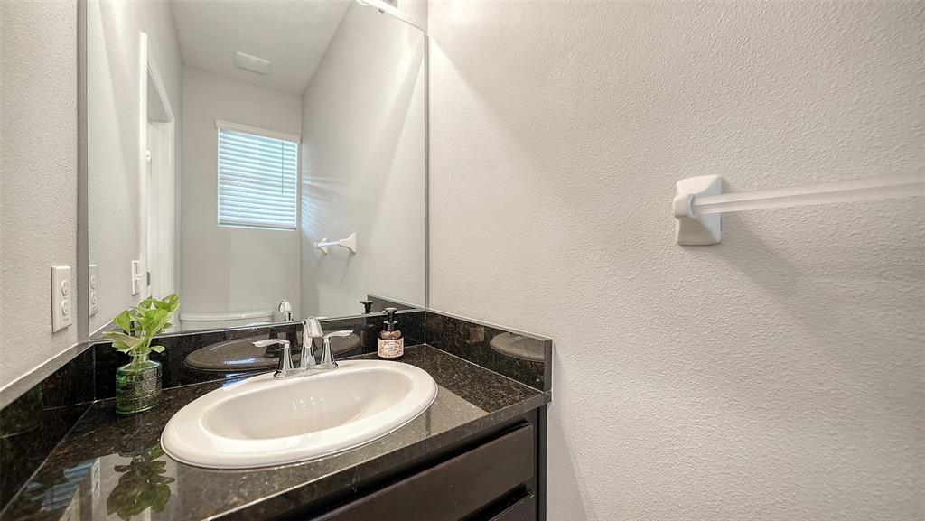 A bathroom features a dark granite vanity countertop, a white oval sink, and a large mirror — 2627 MIDNIGHT PEARL DRIVE, SARASOTA, FL