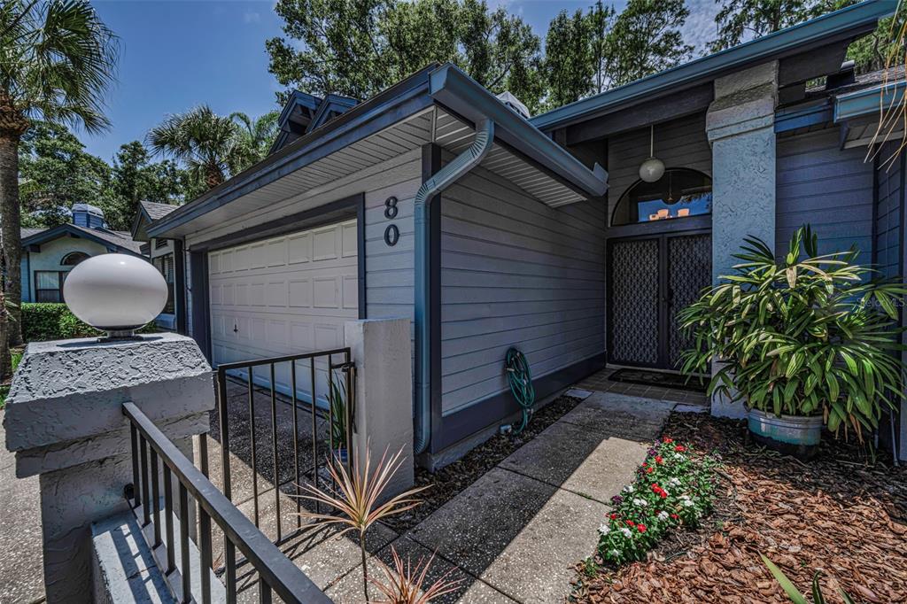 A view of a house exterior featuring a garage, a walkway, and a front entryway — 80 SUMMERWINDS LANE, OLDSMAR, FL