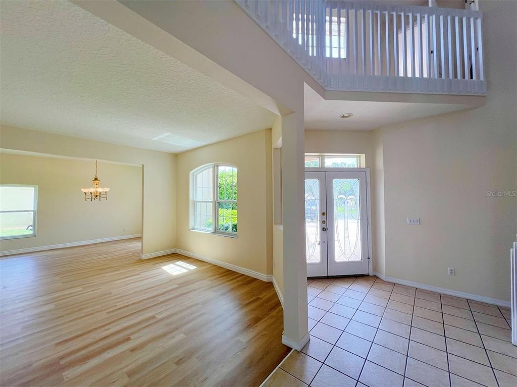 An entryway with tile flooring leads to a living area with light wood-look floors — 2716 GORST RD, WINTER GARDEN, FL