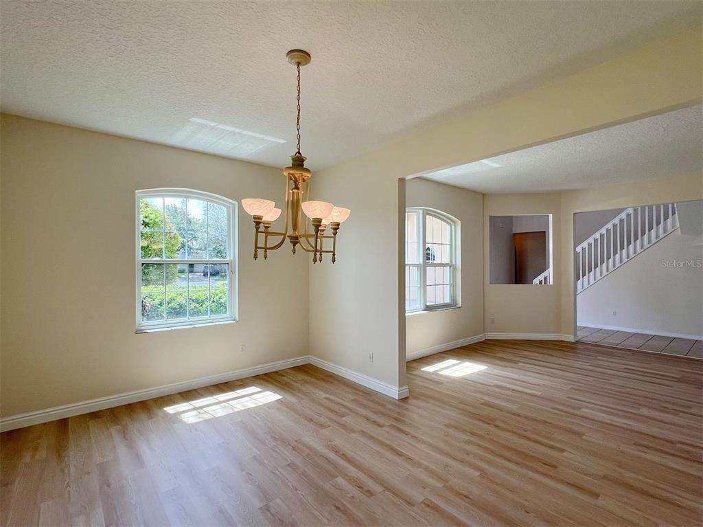 A dining area with light wood flooring, a brass chandelier, and an adjacent staircase — 2716 GORST RD, WINTER GARDEN, FL