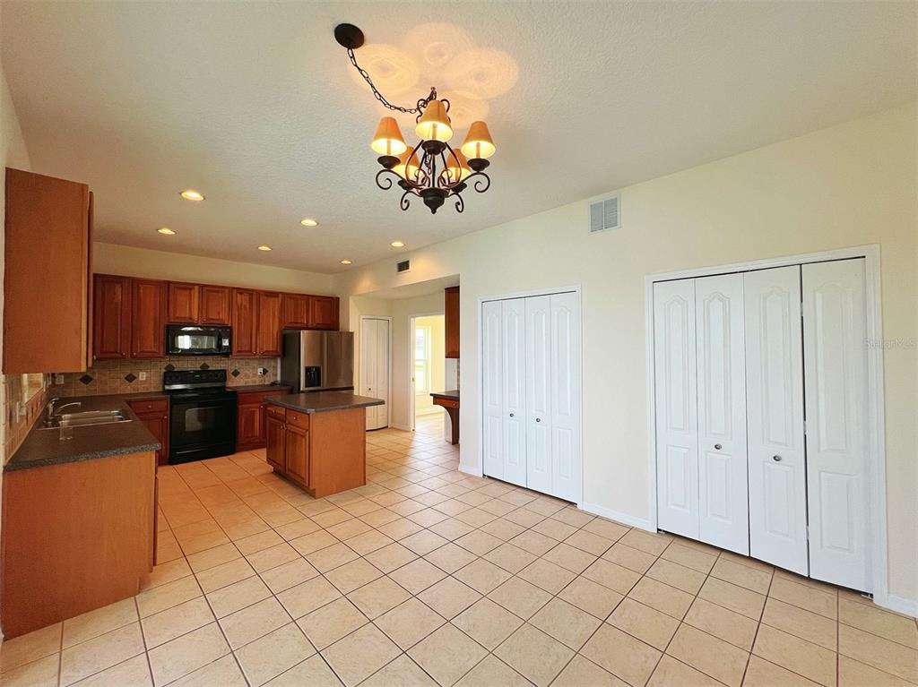 A kitchen with wood cabinets, a center island, and tile flooring opens to a dining area — 2716 GORST RD, WINTER GARDEN, FL