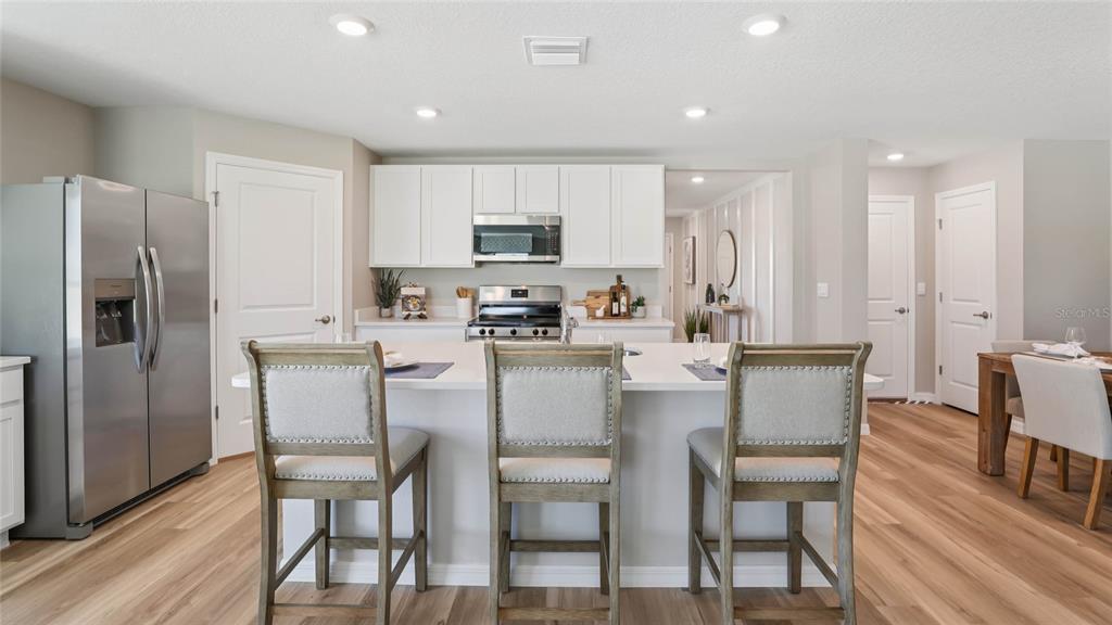 A kitchen features white cabinets, stainless steel appliances, a center island, and three bar stools — 2074 NE 28TH PLACE, OCALA, FL