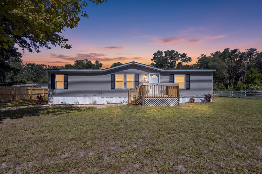 A single-story gray manufactured home with a wooden front deck sits on a grassy lot — 2691 NW 74TH TERRACE, CHIEFLAND, FL