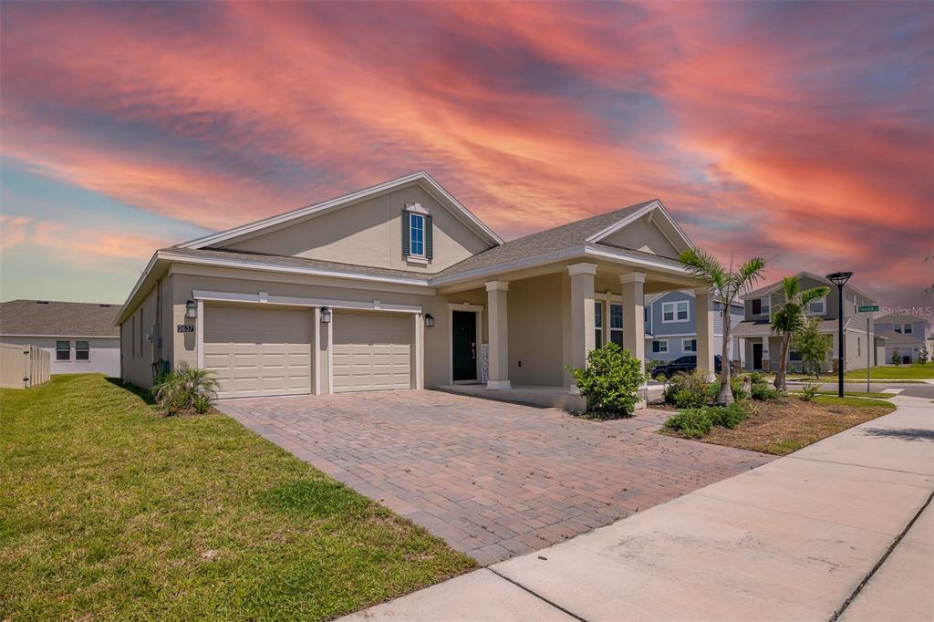 A single-story house with a two-car garage and a paved driveway under a sunset sky — 2637 PEACE OF MIND AVENUE, KISSIMMEE, FL