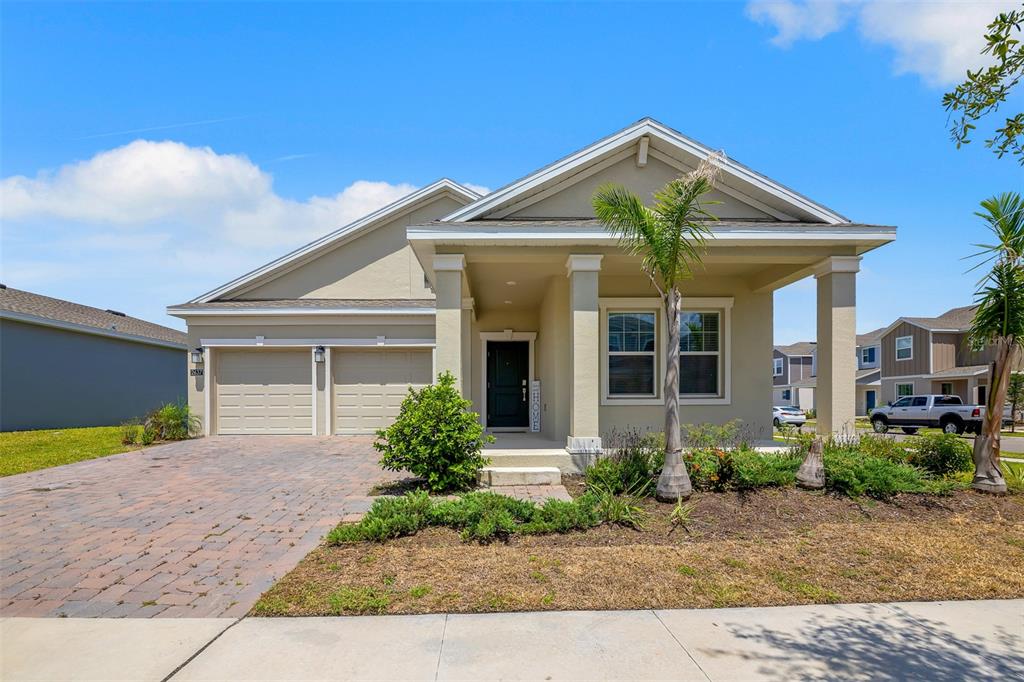 A single-story house with a beige exterior, a two-car garage, and a covered front porch — 2637 PEACE OF MIND AVENUE, KISSIMMEE, FL