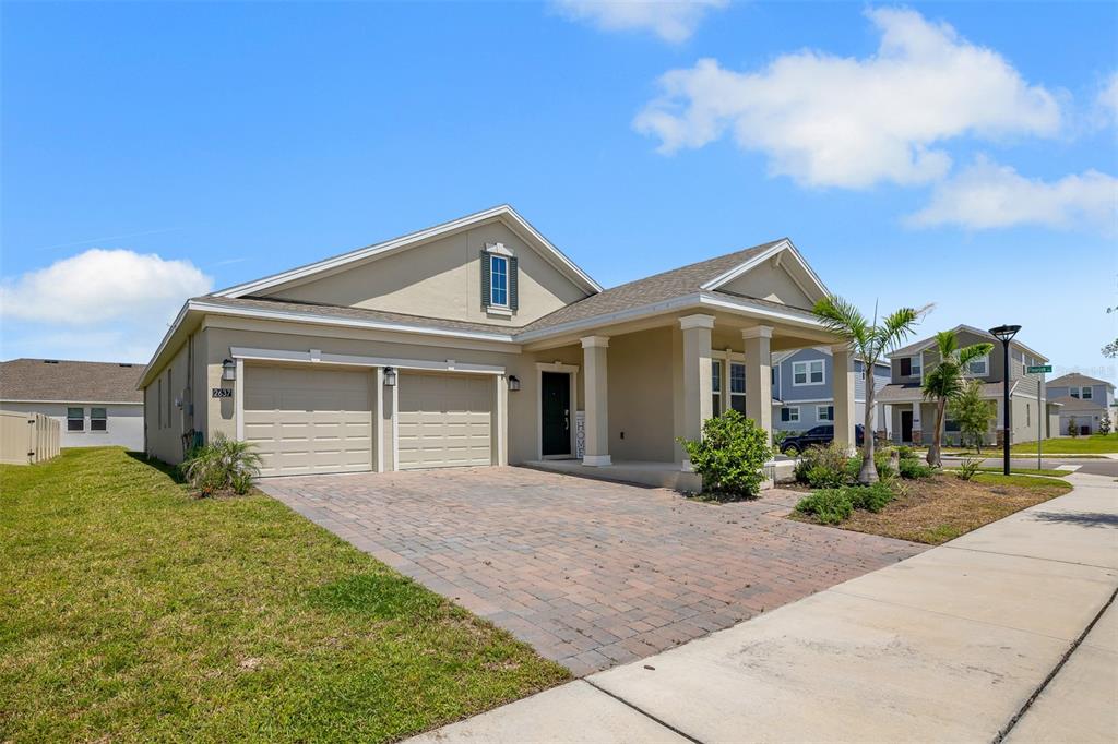 A single-story house with a two-car garage, covered porch, and paved driveway — 2637 PEACE OF MIND AVENUE, KISSIMMEE, FL