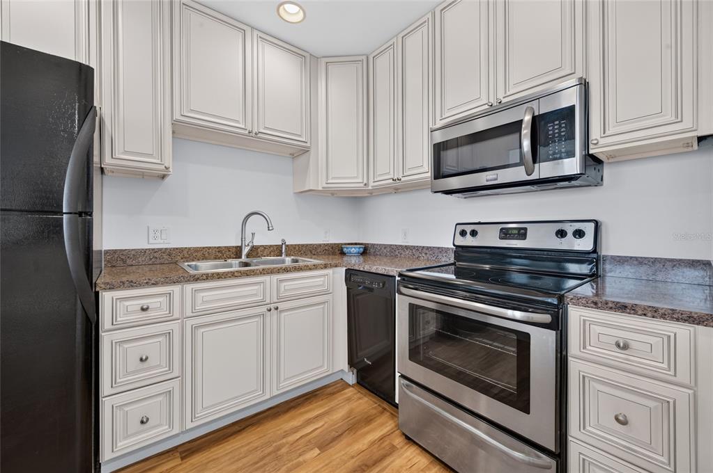 A kitchen with white cabinets, granite countertops, and black and stainless steel appliances — 935 N HALIFAX AVENUE UNIT 1105, DAYTONA BEACH, FL