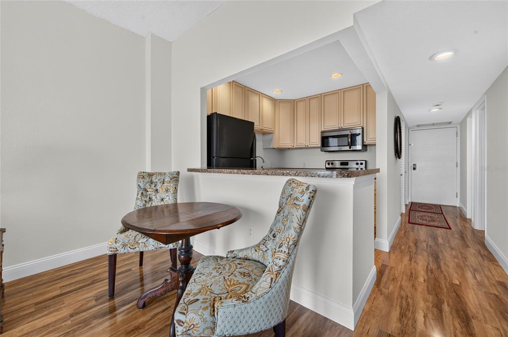 A small dining area with a round table and two patterned chairs faces a kitchen pass-through — 935 N HALIFAX AVENUE UNIT 1105, DAYTONA BEACH, FL