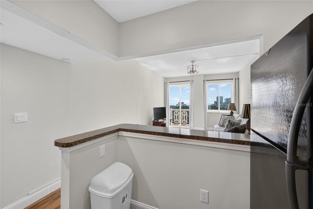 A kitchen counter overlooks a living area with a balcony and a view of buildings — 935 N HALIFAX AVENUE UNIT 1105, DAYTONA BEACH, FL
