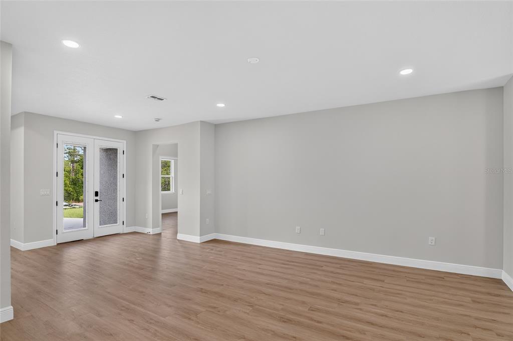 An open-concept living, dining, and kitchen area with light wood floors and blue cabinetry — 4 LONE PINE STREET, HOMOSASSA, FL