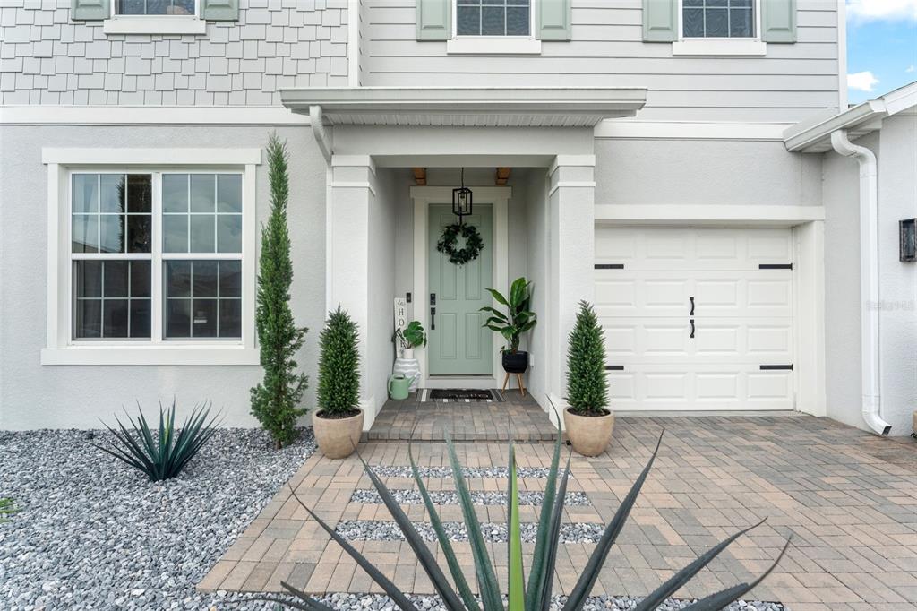 The exterior of a house features a light green door, a paved walkway, and landscaping — 2640 HILLTOP LOOP, APOPKA, FL