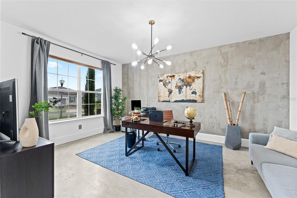 A home office features a concrete accent wall, a dark wood desk, and a blue rug — 2640 HILLTOP LOOP, APOPKA, FL
