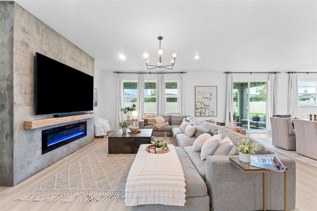 A living room features a concrete accent wall with a television and electric fireplace — 2640 HILLTOP LOOP, APOPKA, FL