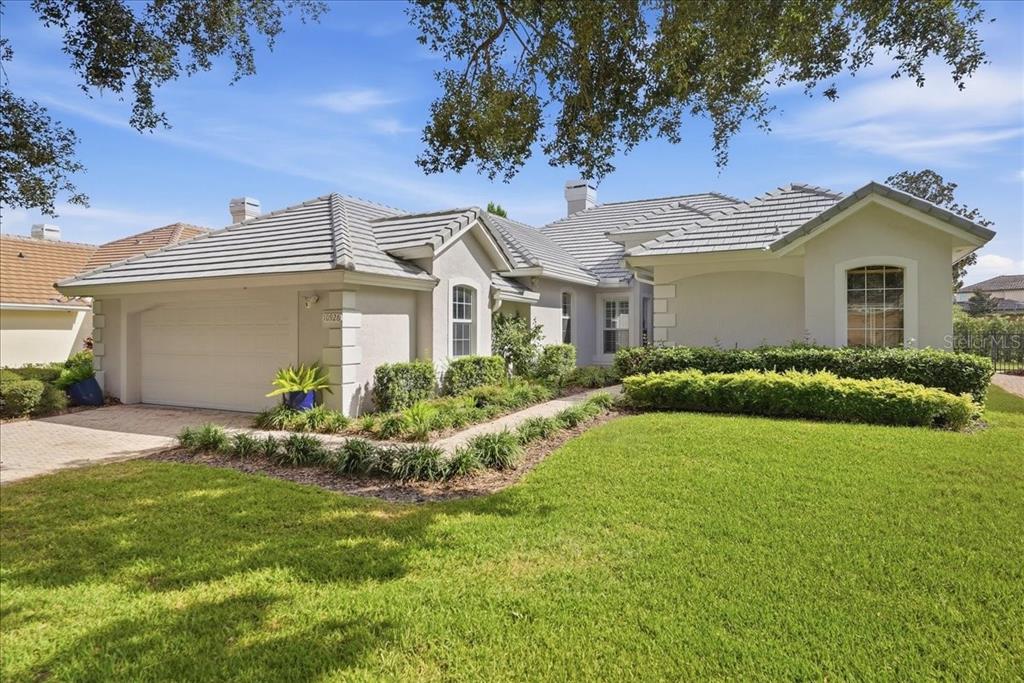 A single-story house with a tiled roof, two-car garage, and a manicured front lawn — 10926 WOODCHASE CIRCLE, ORLANDO, FL