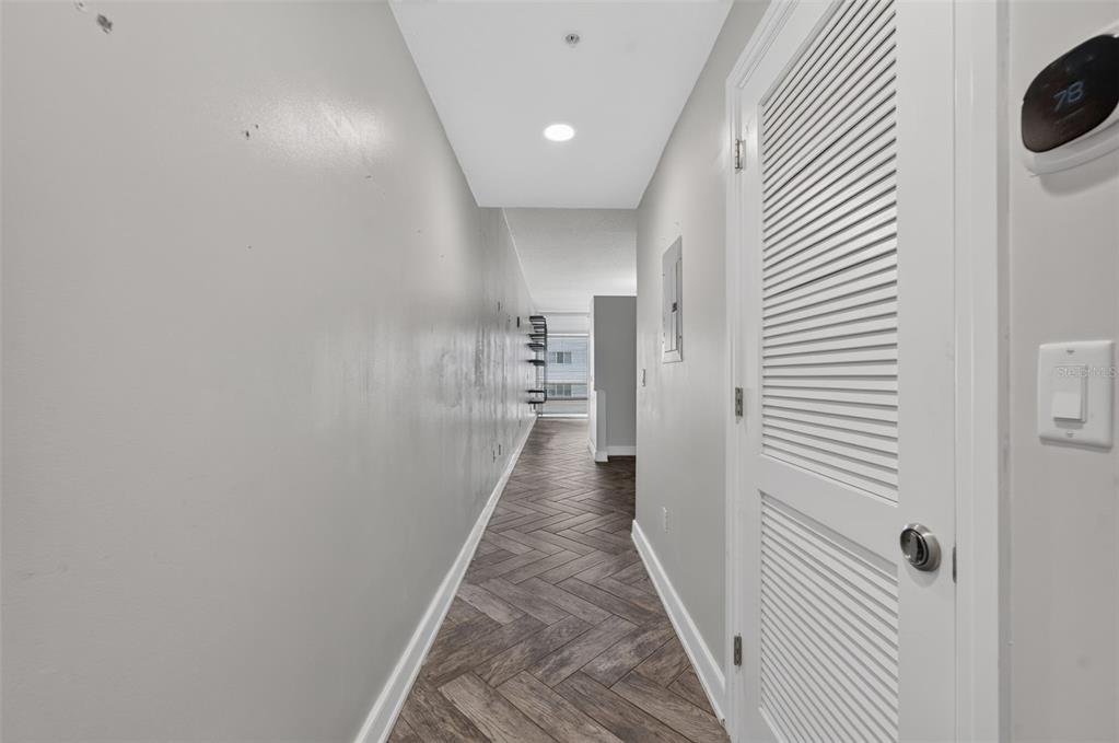A hallway with gray walls, herringbone-patterned flooring, and a louvered door closet — 101 S EOLA DRIVE UNIT 1016, ORLANDO, FL