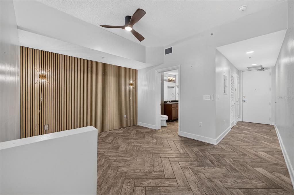 A room with wood-slat wall paneling, herringbone-patterned flooring, and a ceiling fan — 101 S EOLA DRIVE UNIT 1016, ORLANDO, FL