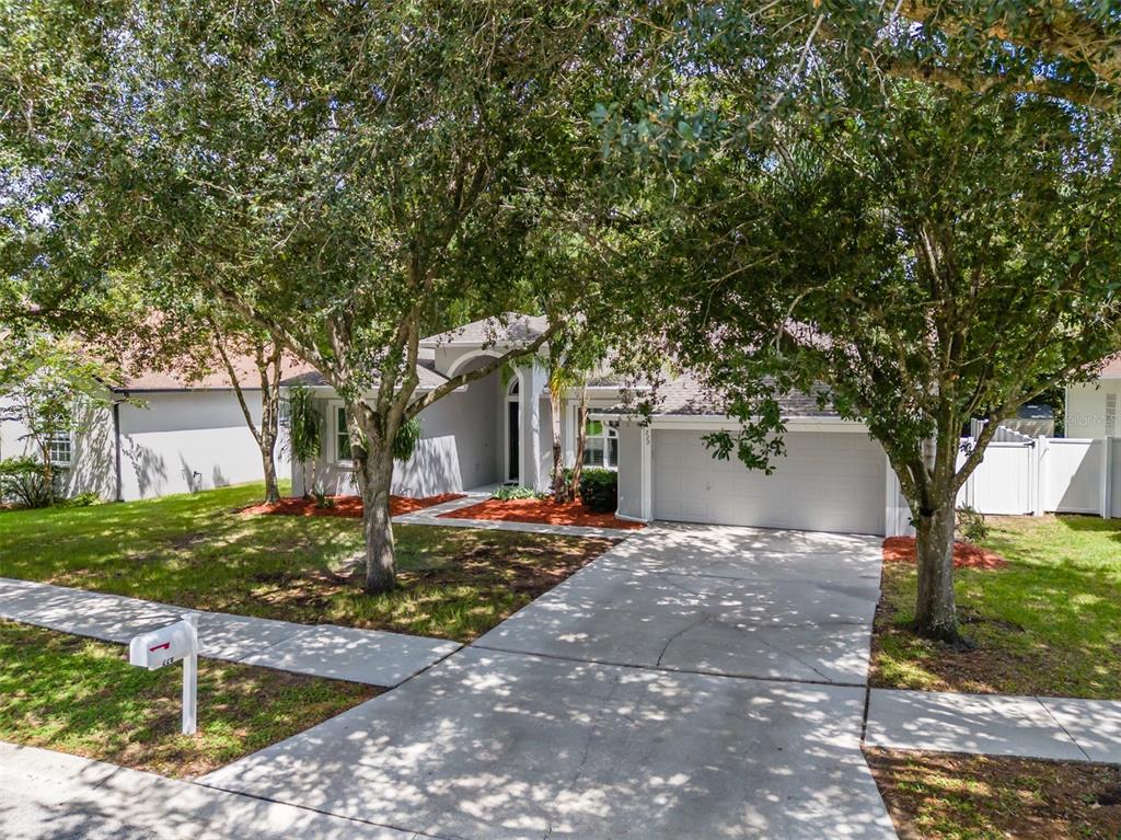 A one-story house with a gray garage, concrete driveway, and large trees in the front yard — 220 TAYLOR BAY LANE, BRANDON, FL