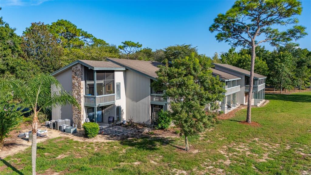 A two-story apartment building features stone pillars, wooden railings, and an American flag — 3558 CAMELOT DRIVE UNIT 3558, HAINES CITY, FL