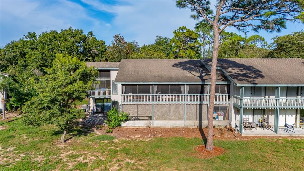 A two-story building exterior features a wooden staircase, a stone pillar, and a concrete walkway — 3558 CAMELOT DRIVE UNIT 3558, HAINES CITY, FL