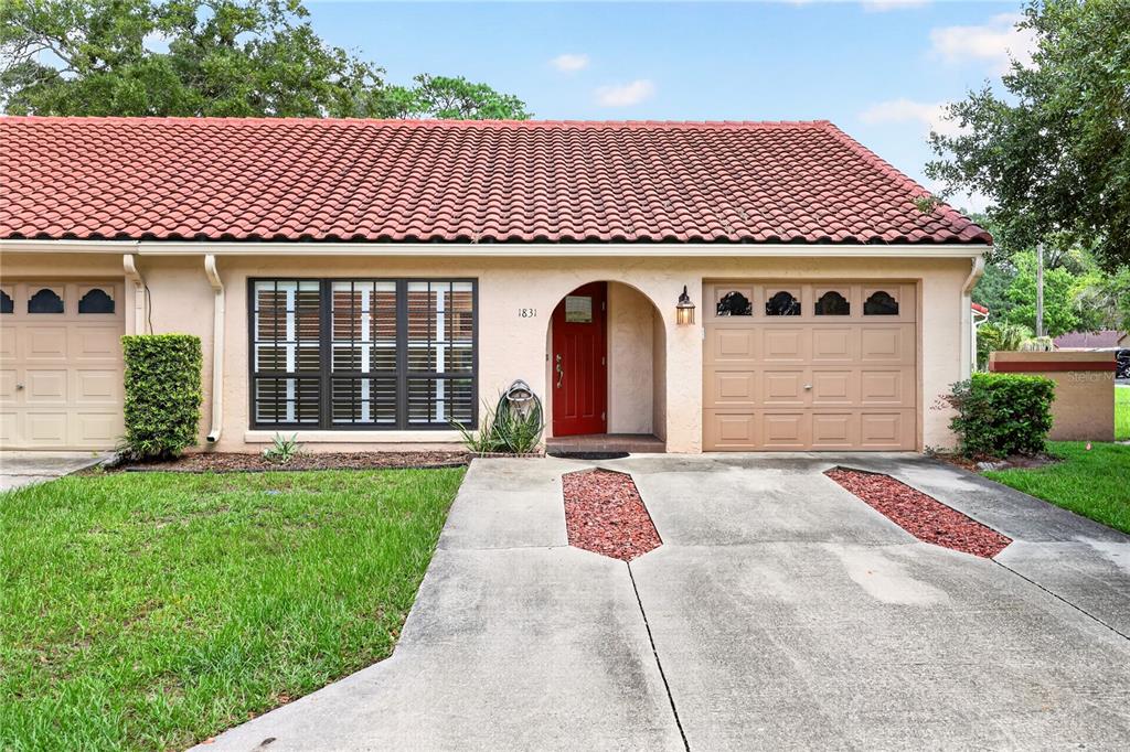 A single-story house with a red tile roof, a red front door, and a two-car garage — 1831 SW 35TH AVENUE, OCALA, FL