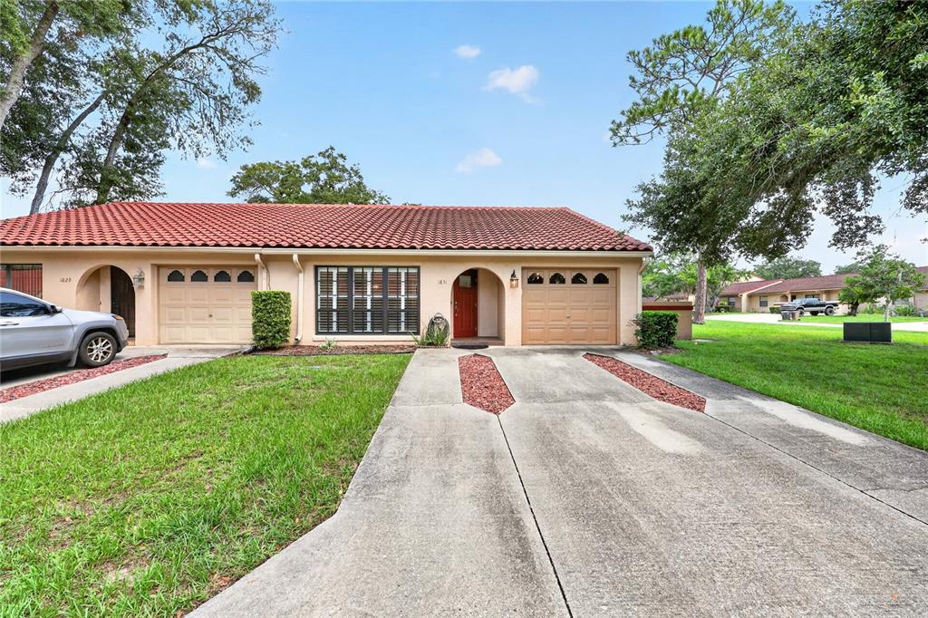 A single-story duplex with a red tile roof, two garages, and a concrete driveway — 1831 SW 35TH AVENUE, OCALA, FL