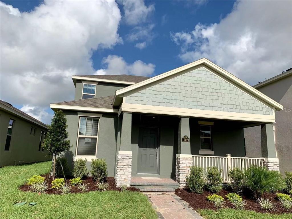 A two-story house with a green stucco exterior, stone accents, and a covered front porch — 10071 TAWNY MEADOW ALLEY, WINTER GARDEN, FL