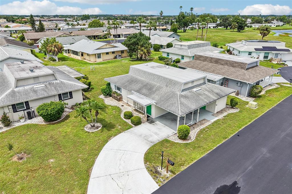 An aerial view shows a single-story house with a carport and driveway in a neighborhood — 704 RADFORD PLACE, SUN CITY CENTER, FL