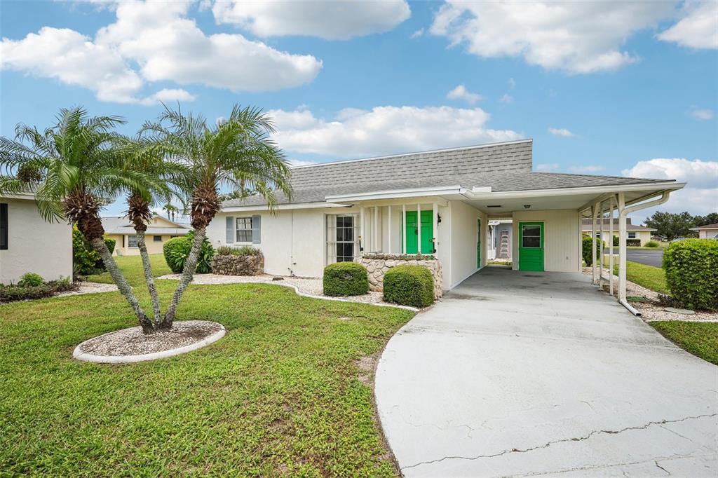 A single-story house with a white exterior, green doors, and a concrete carport — 704 RADFORD PLACE, SUN CITY CENTER, FL